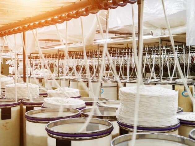 fabric threads being pulled from barrels.